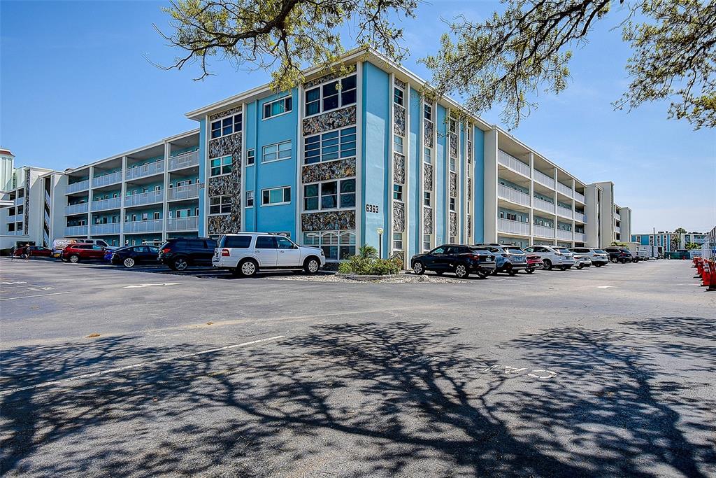 A multi-story blue apartment building with a parking lot in the foreground — 6363 GULF WINDS DRIVE UNIT 327, ST PETE BEACH, FL