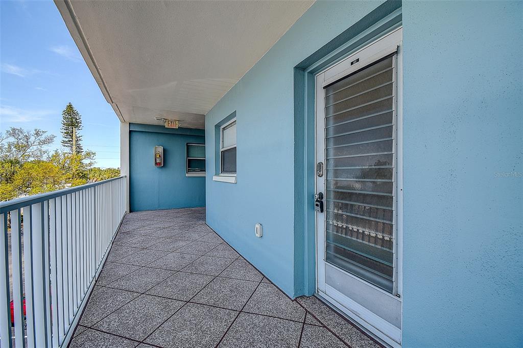 An outdoor balcony with blue walls, a white railing, and a glass-paneled door — 6363 GULF WINDS DRIVE UNIT 327, ST PETE BEACH, FL
