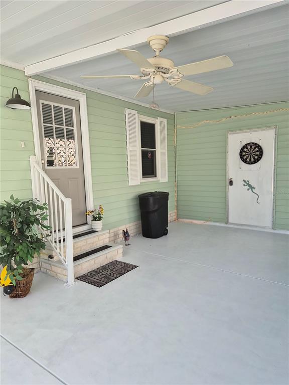 A covered porch with light green siding, a ceiling fan, and two exterior doors — 508 SAINT ANDREWS BOULEVARD, LADY LAKE, FL