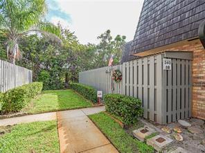 A concrete walkway leads past a fenced patio area and a small lawn with hedges — 340 S Waverly Place # 8b, Vero Beach FL 32960, VERO BEACH, FL
