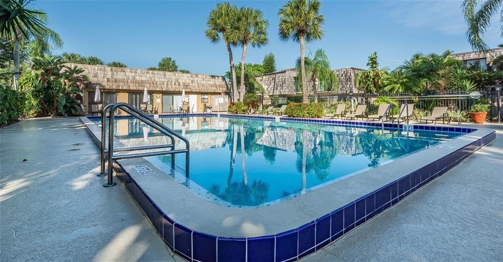 An outdoor swimming pool with a metal ladder is surrounded by a patio and palm trees — 340 S Waverly Place # 8b, Vero Beach FL 32960, VERO BEACH, FL