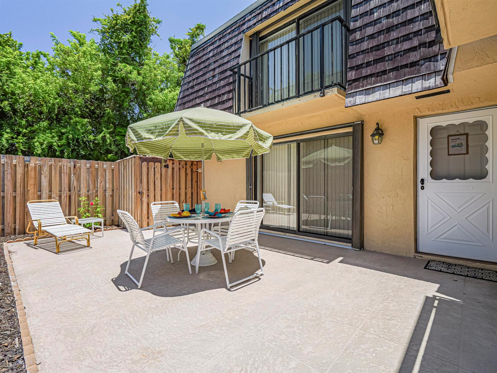 A patio features a dining set with a green umbrella, a lounge chair, and a door — 340 S Waverly Place # 8b, Vero Beach FL 32960, VERO BEACH, FL