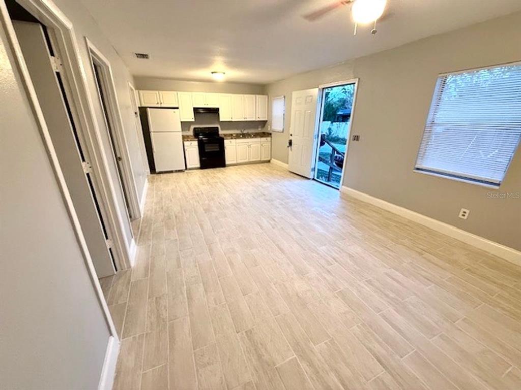 An open-concept kitchen and living area features light wood-look tile flooring and white cabinetry — 5228 CHERRY AVENUE UNIT B, SEFFNER, FL