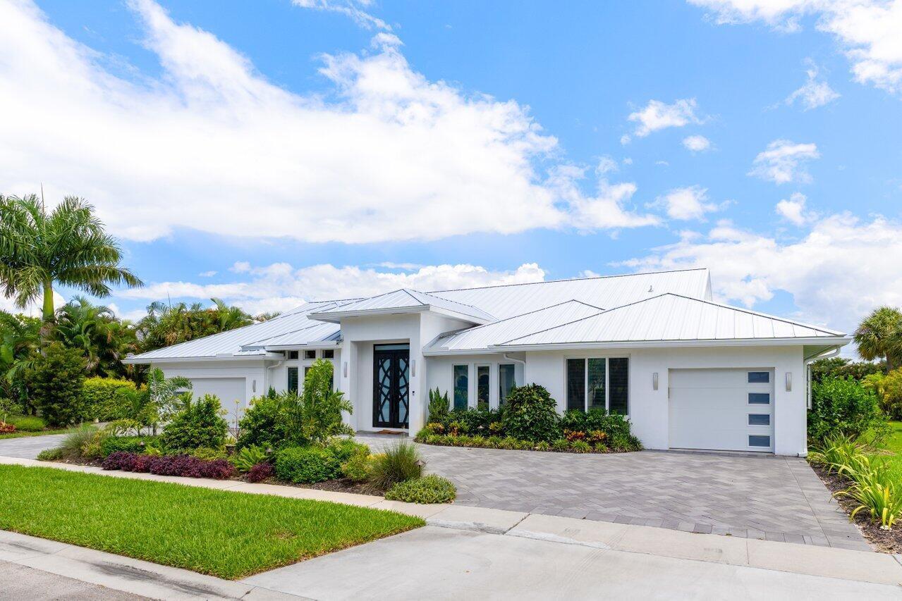 A white single-story house with a metal roof, paved driveway, and lush landscaping — 11164 Boca Woods Lane, Boca Raton FL 33428, BOCA RATON, FL
