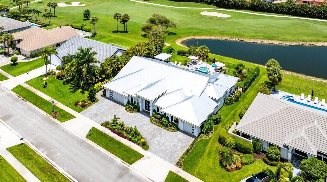 An aerial view shows a white-roofed house with a paved driveway next to a pond — 11164 Boca Woods Lane, Boca Raton FL 33428, BOCA RATON, FL
