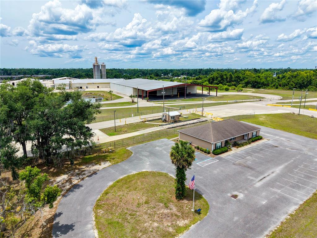 An aerial view shows a commercial building with a parking lot and industrial structures nearby — 1509 S BYRON BUTLER PARKWAY, PERRY, FL
