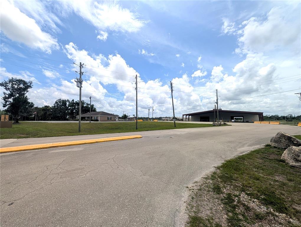 A paved road leads toward a large metal building and a smaller house under clouds — 1509 S BYRON BUTLER PARKWAY, PERRY, FL