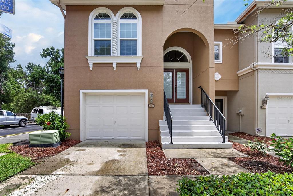 A tan two-story townhouse features a single-car garage, white stairs, and a double-door entrance — 307 SUMMER CLOUDS PLACE, BRANDON, FL