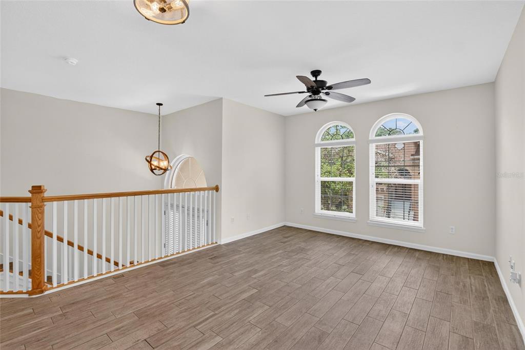 An upstairs loft area features wood-look tile flooring, a ceiling fan, and arched windows — 307 SUMMER CLOUDS PLACE, BRANDON, FL