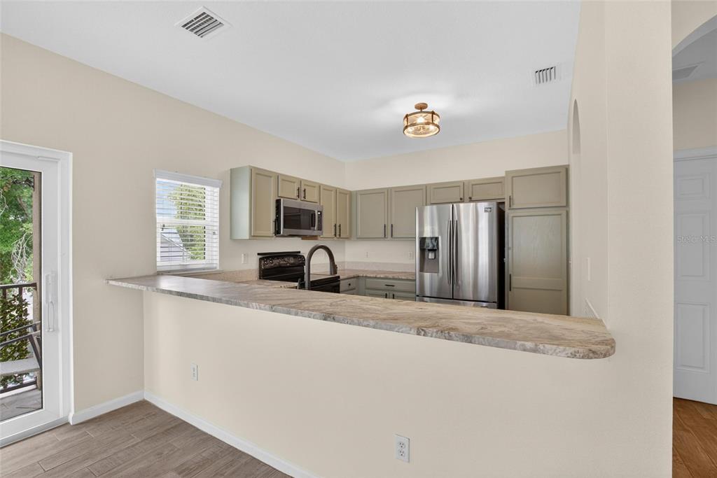 A kitchen features light-colored cabinets, stainless steel appliances, and a stone-topped breakfast bar — 307 SUMMER CLOUDS PLACE, BRANDON, FL