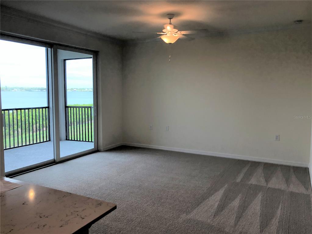 An empty room with beige carpet, a ceiling fan, and a sliding door to a balcony — 1010 TIDEWATER SHORES LOOP UNIT 206, BRADENTON, FL
