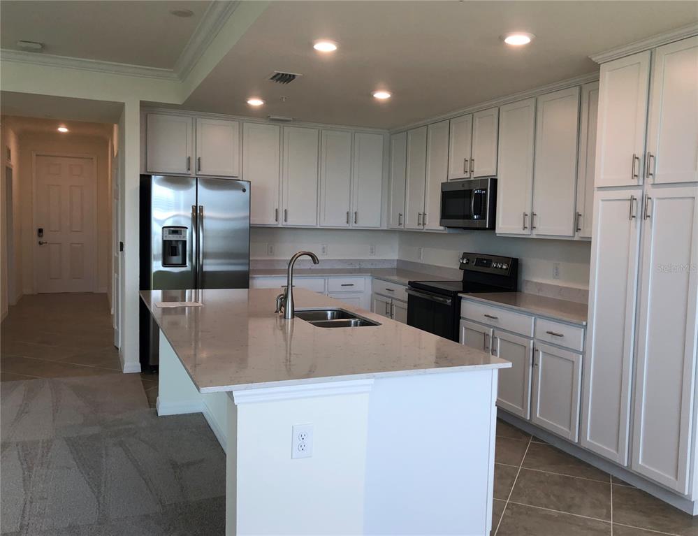 A kitchen with white cabinets, stainless steel appliances, and a large island with a sink — 1010 TIDEWATER SHORES LOOP UNIT 206, BRADENTON, FL