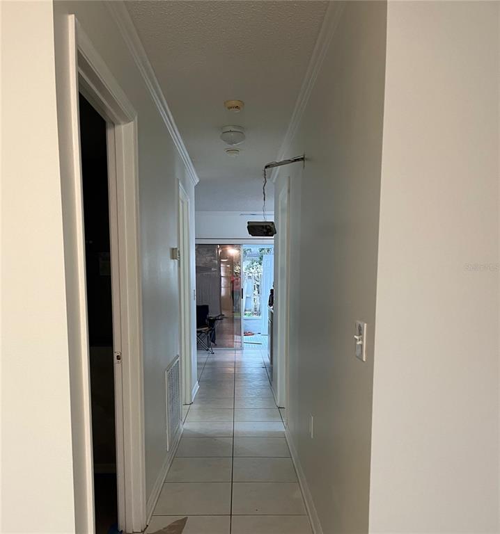 A hallway with light-colored tile flooring leads toward a glass sliding door at the end — 3021 W TAMPA BAY BOULEVARD, TAMPA, FL