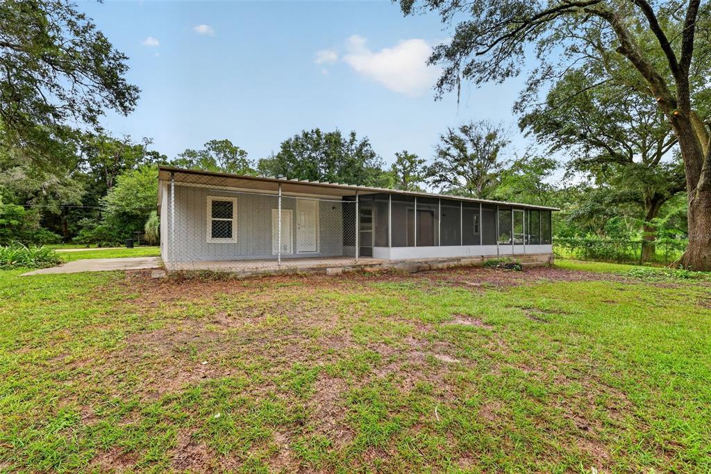 The exterior of a single-story house features a chain-link enclosed patio and a screened porch — 2888 SE 59TH STREET, OCALA, FL
