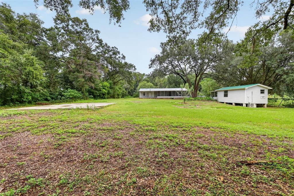 A grassy yard features a concrete slab, a long house, and a smaller detached structure — 2888 SE 59TH STREET, OCALA, FL