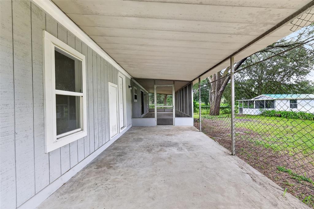 A covered concrete patio with gray vertical siding and a chain-link fence enclosure — 2888 SE 59TH STREET, OCALA, FL