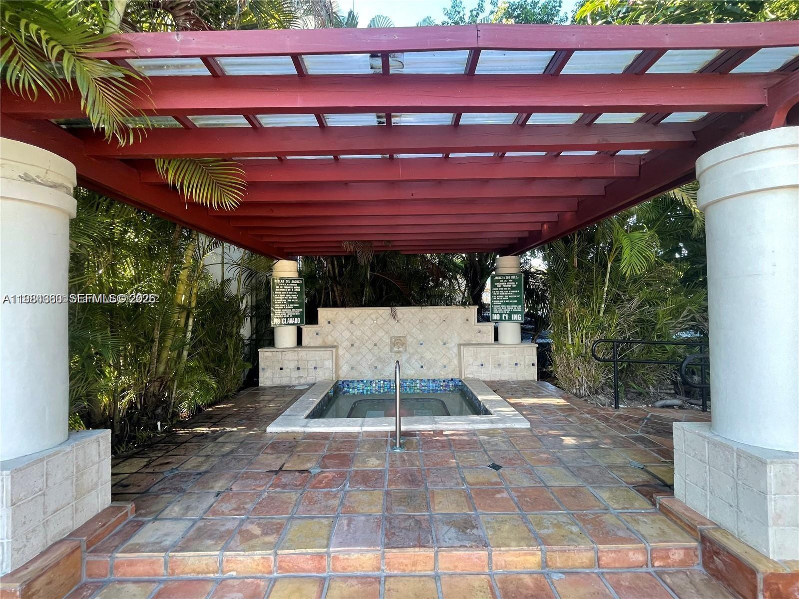 A rectangular hot tub sits under a red wooden pergola on a tiled patio — 10431 N Kendall Dr # D314, Miami FL 33176, MIAMI, FL