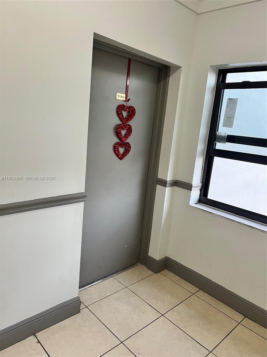 A gray door with a heart decoration is located in a tiled hallway — 10431 N Kendall Dr # D314, Miami FL 33176, MIAMI, FL