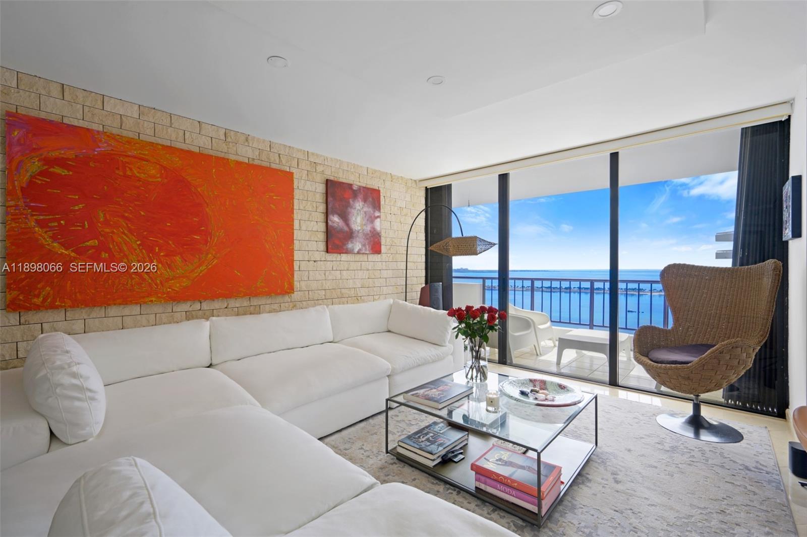 A living room features a white sectional sofa, brick wall, and balcony with ocean views — 1581 Brickell Ave # 2005, Miami FL 33129, MIAMI, FL