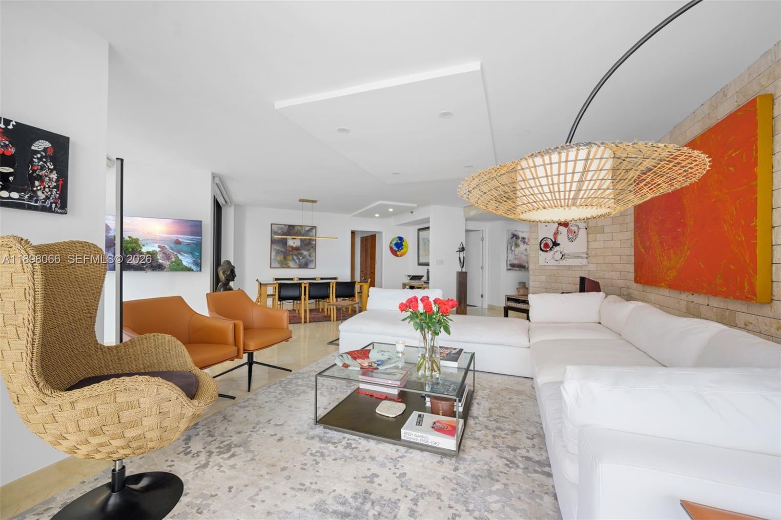 A modern living room features a white sectional sofa, orange armchairs, and a large pendant light — 1581 Brickell Ave # 2005, Miami FL 33129, MIAMI, FL