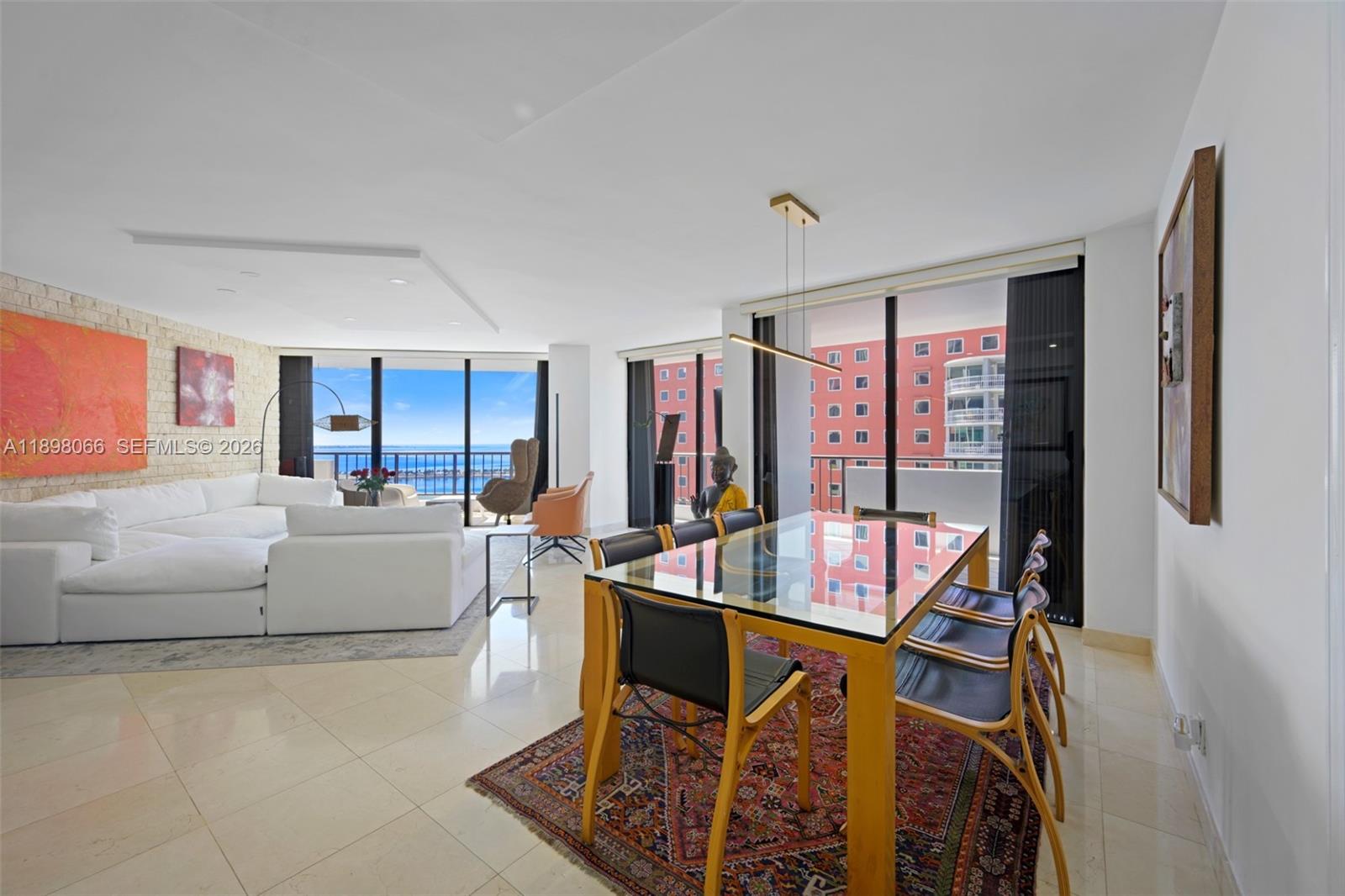 A bright living and dining area features tile floors, a glass table, and ocean views — 1581 Brickell Ave # 2005, Miami FL 33129, MIAMI, FL