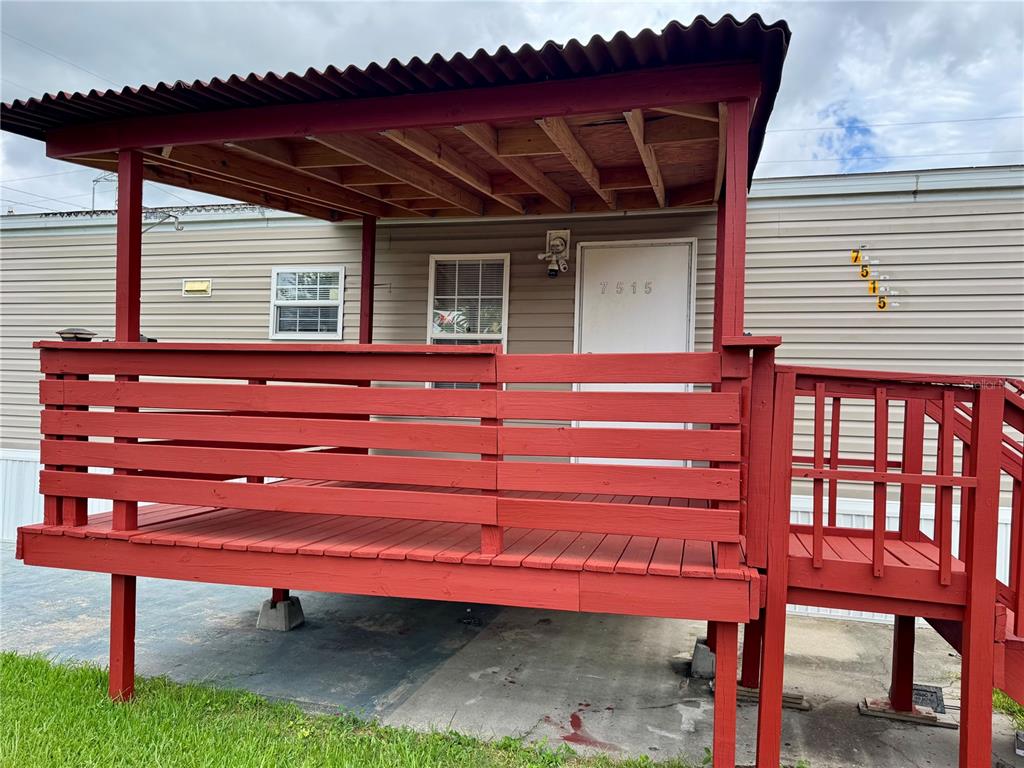 A red wooden deck with a covered porch stands in front of a tan mobile home — 7515 RANCHERO STREET, ORLANDO, FL