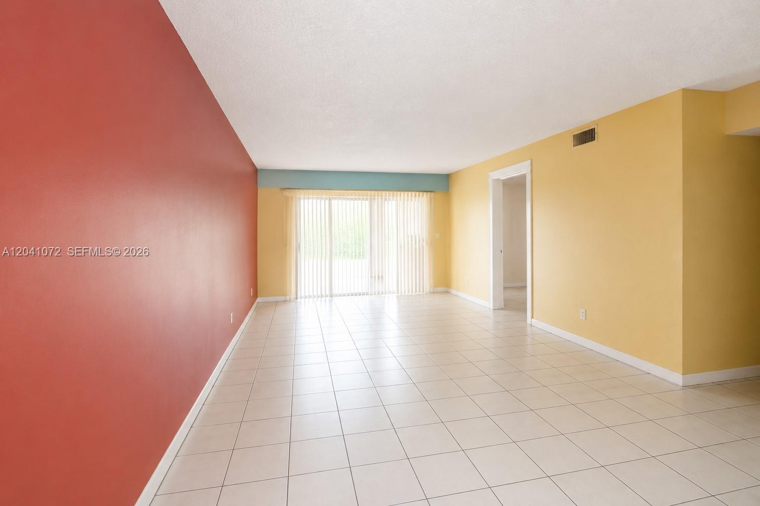 An empty room features a red wall, yellow walls, white tile flooring, and vertical blinds — 1975 W 44th Pl # 310, Hialeah FL 33012, HIALEAH, FL