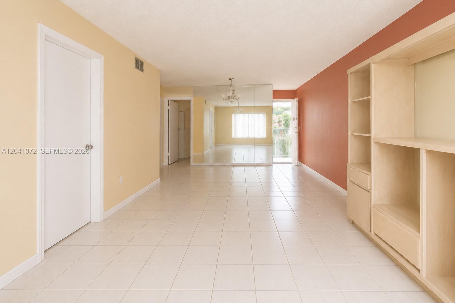 A living room features light-colored tile floors, a mirrored wall, and a built-in wooden unit — 1975 W 44th Pl # 310, Hialeah FL 33012, HIALEAH, FL
