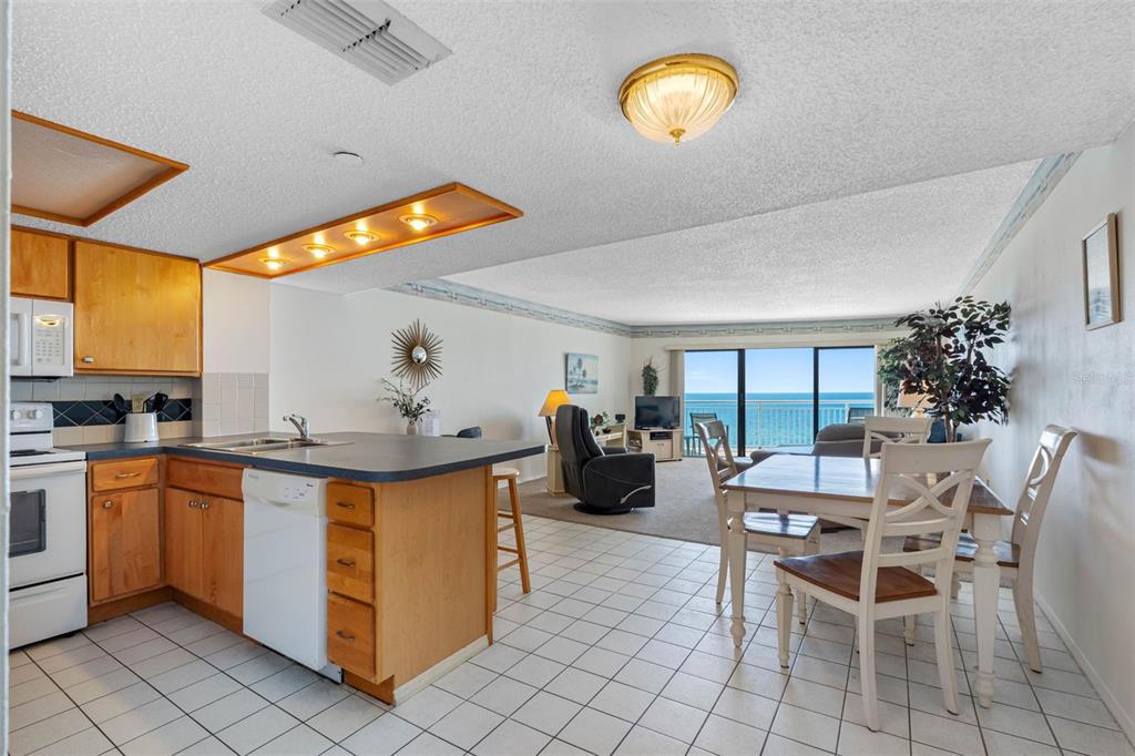 An open-concept kitchen with wood cabinets and a dining area overlooking the ocean — 19440 GULF BOULEVARD UNIT 506, INDIAN ROCKS BEACH, FL