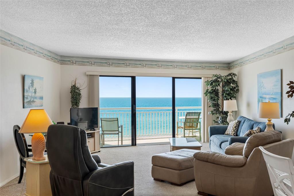 A living room with a blue sofa, recliner, and sliding glass doors overlooking the ocean — 19440 GULF BOULEVARD UNIT 506, INDIAN ROCKS BEACH, FL