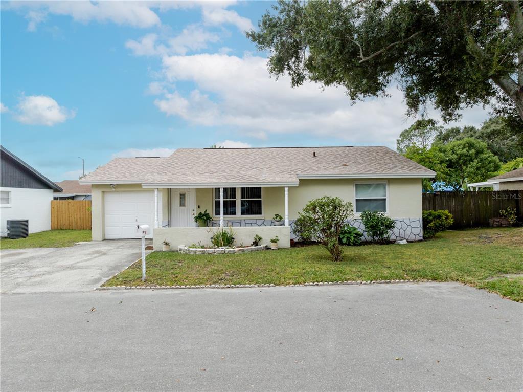 A single-story house with a light yellow exterior, a white garage door, and a front porch — 10118 HUNTERS POINT COURT, TAMPA, FL
