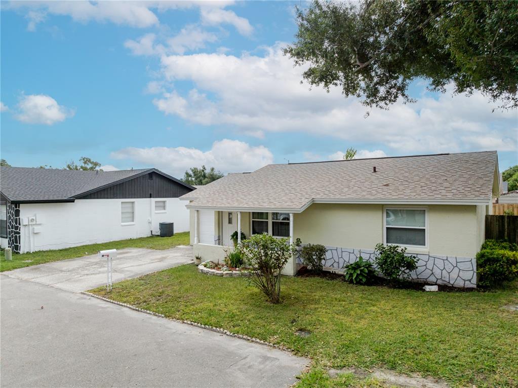 A light yellow, single-story house with a stone-patterned base and a concrete driveway — 10118 HUNTERS POINT COURT, TAMPA, FL