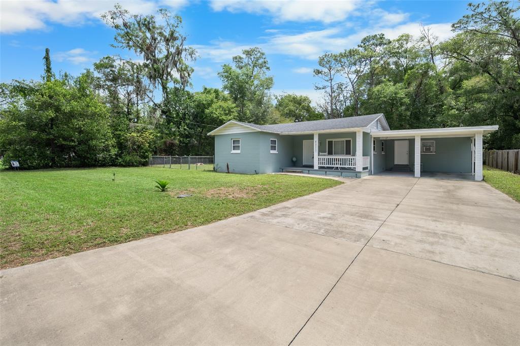A single-story house with a light green exterior, a front porch, and a concrete driveway — 4323 NW 12TH TERRACE, GAINESVILLE, FL