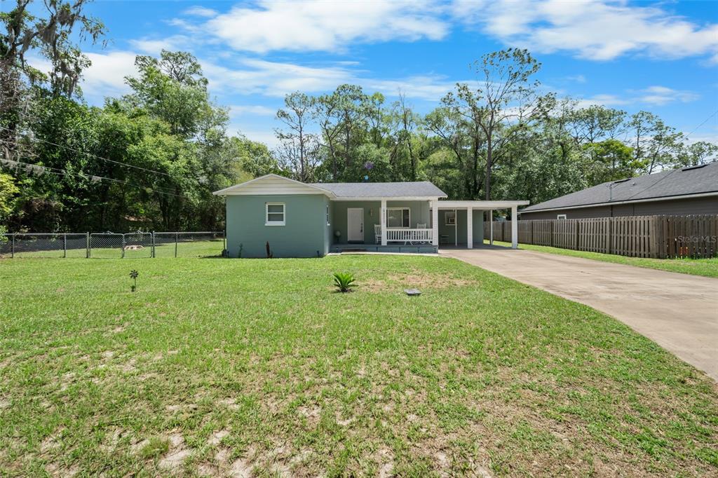 A single-story house with a green exterior, a front porch, and an attached carport — 4323 NW 12TH TERRACE, GAINESVILLE, FL