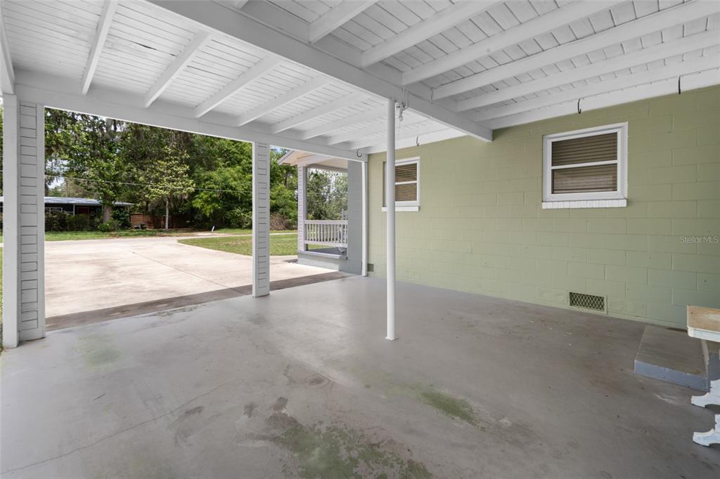 A covered concrete patio features a green block wall, white ceiling beams, and support posts — 4323 NW 12TH TERRACE, GAINESVILLE, FL