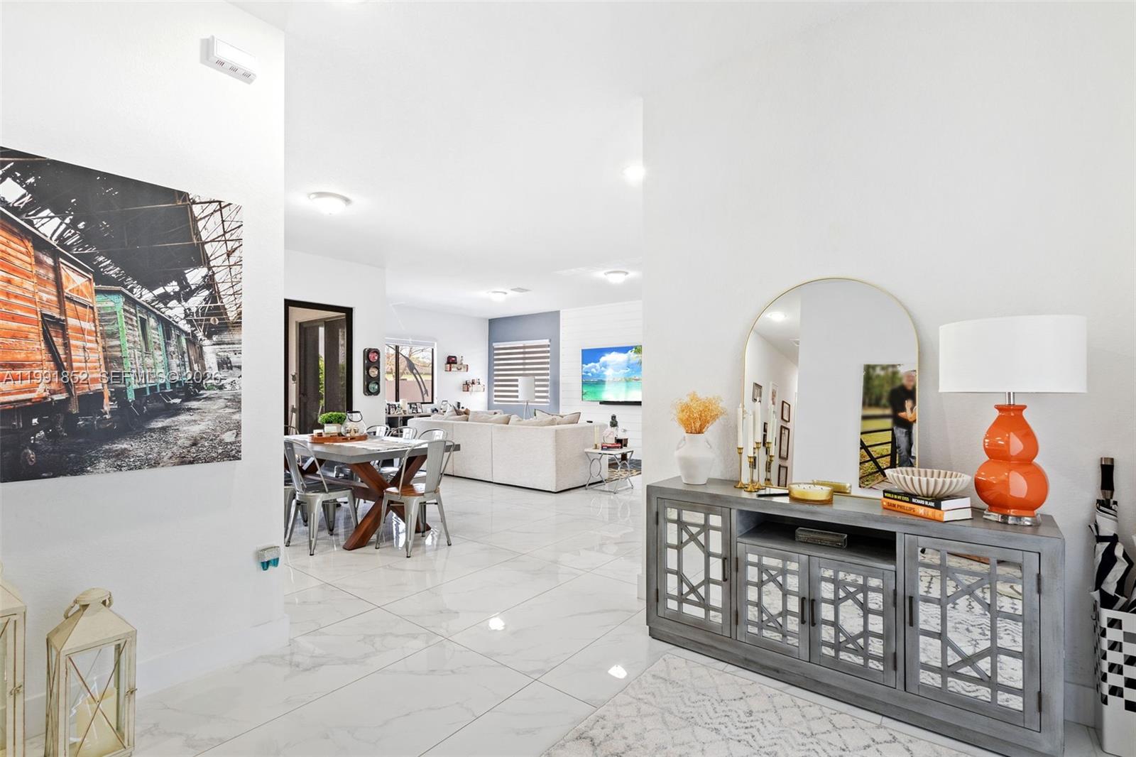 A bright, open-concept living area features white marble floors, a gray sideboard, and dining furniture — 13217 SW 227th St, Miami FL 33170, MIAMI, FL