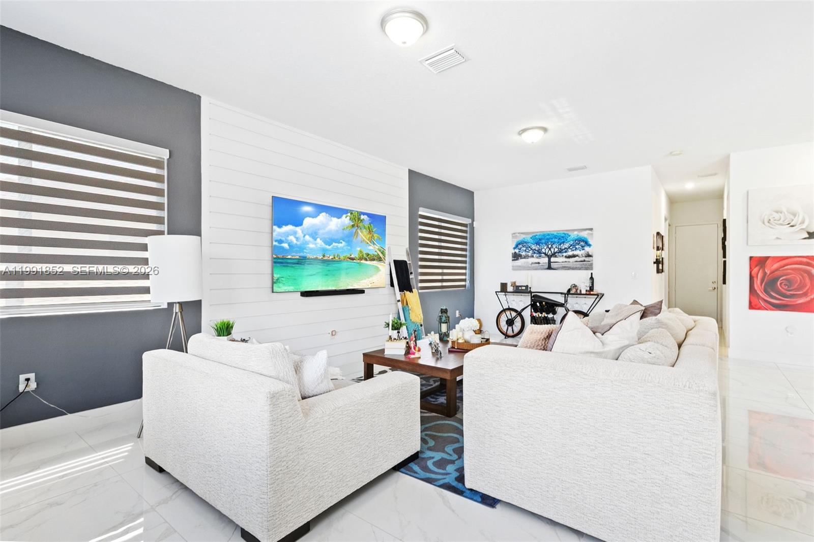 A living room features a white shiplap accent wall with a mounted television and sofa — 13217 SW 227th St, Miami FL 33170, MIAMI, FL