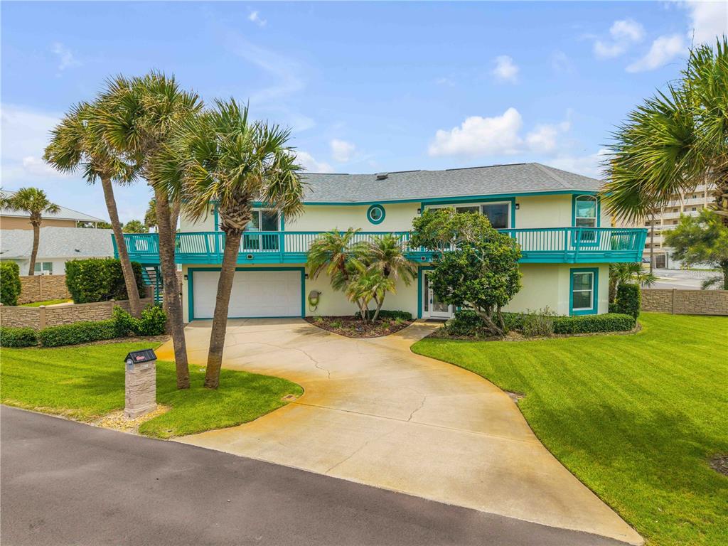 A two-story house with a teal balcony, a concrete driveway, and palm trees — 320 DUE EAST STREET, NEW SMYRNA BEACH, FL