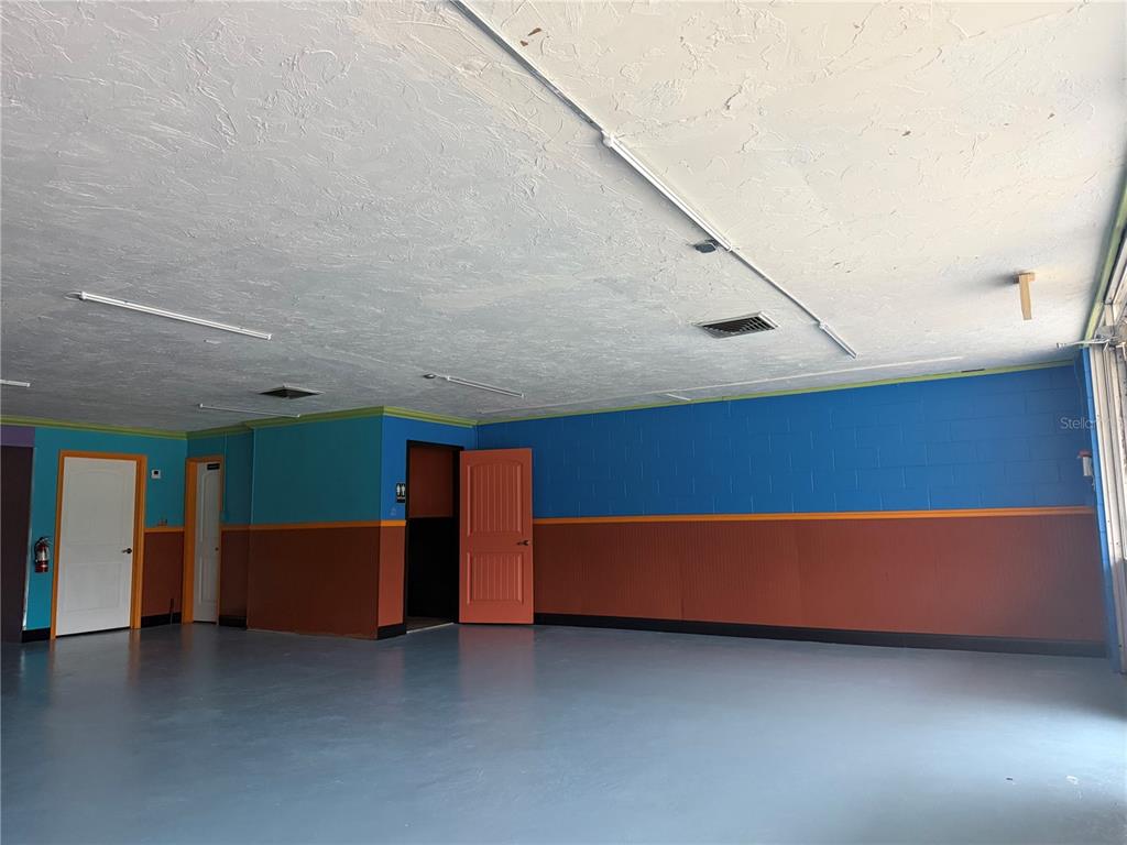 A garage with a gray floor, blue and brown walls, and multiple interior doors — 515 S MAIN STREET, CHIEFLAND, FL