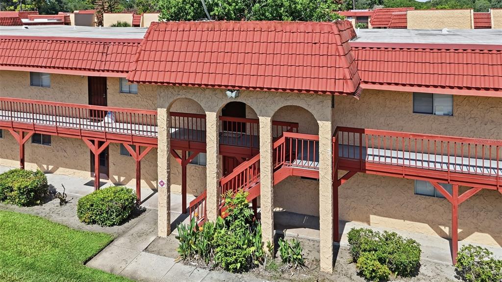 An exterior view of a two-story apartment building with red tile roofing and wooden balconies — 2868 N POWERS DRIVE UNIT 177, ORLANDO, FL