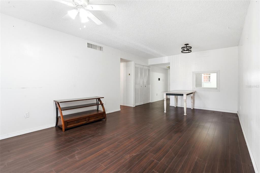 A living room with white walls, dark wood-look flooring, a ceiling fan, and a console table — 2868 N POWERS DRIVE UNIT 177, ORLANDO, FL