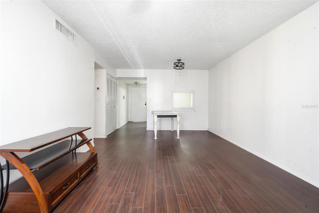 An empty room features dark wood-look flooring, white walls, a ceiling light, and a table — 2868 N POWERS DRIVE UNIT 177, ORLANDO, FL