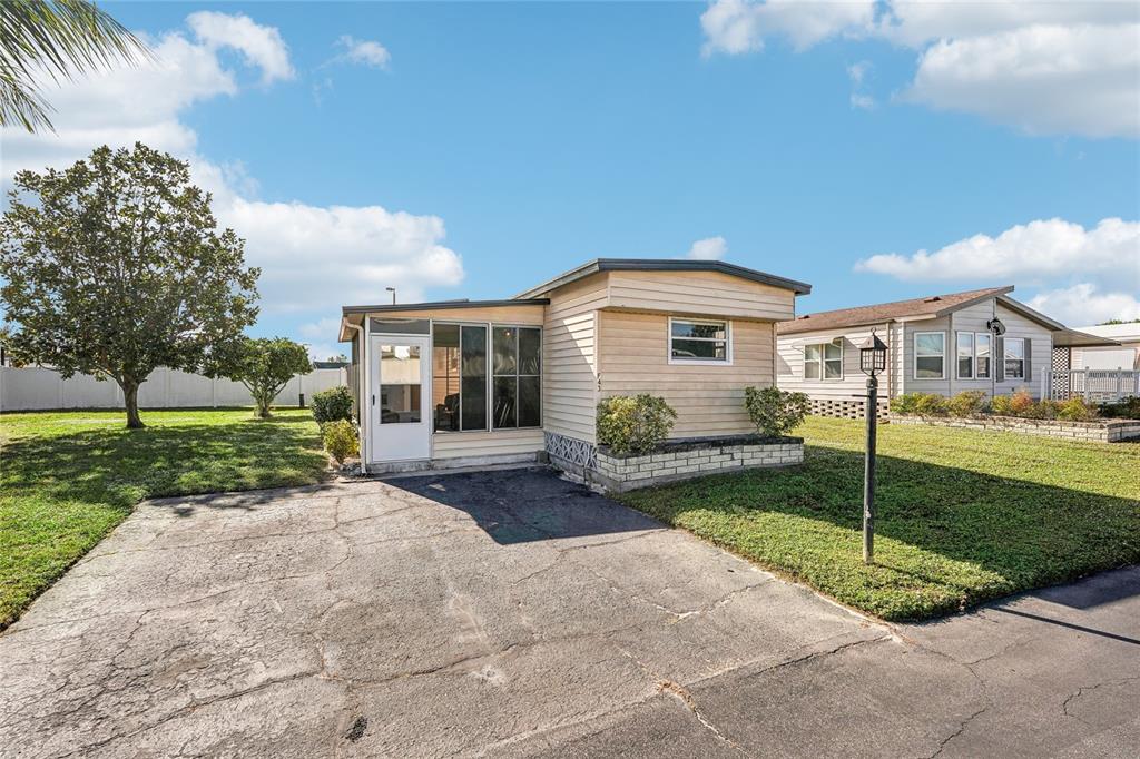 A single-story mobile home with a paved driveway, screened-in porch, and a grassy yard — 5316 53RD AVENUE E UNIT F43, BRADENTON, FL