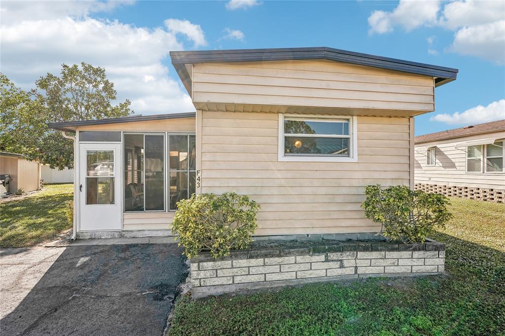 A single-story mobile home with tan siding, a screened-in porch, and a brick planter box — 5316 53RD AVENUE E UNIT F43, BRADENTON, FL