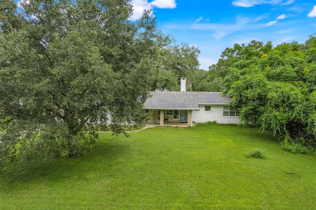 A single-story white brick house sits behind a large tree on a grassy lawn — 1148 PEARL VIEW DRIVE, ALTAMONTE SPRINGS, FL