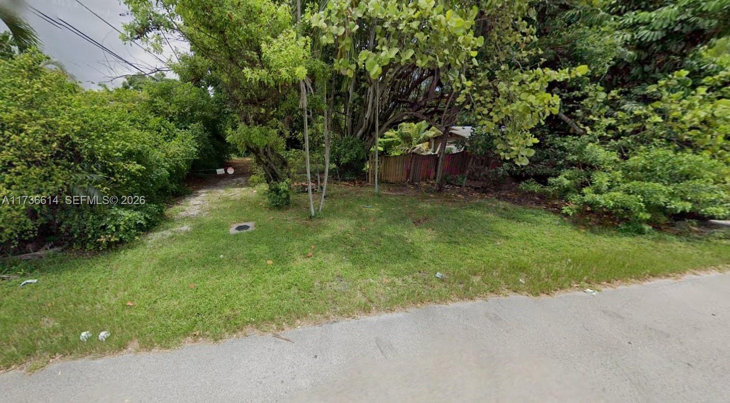 A grassy, tree-lined vacant lot sits adjacent to a paved road and wooden fence — 2361 SW 45th St, Dania Beach FL 33312, DANIA BEACH, FL