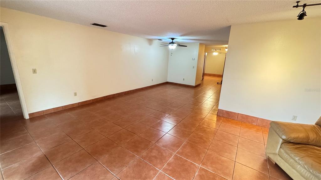 A spacious living room features light-colored walls, a ceiling fan, and brown tile flooring — 2657 EXUMA WAY, WINTER PARK, FL