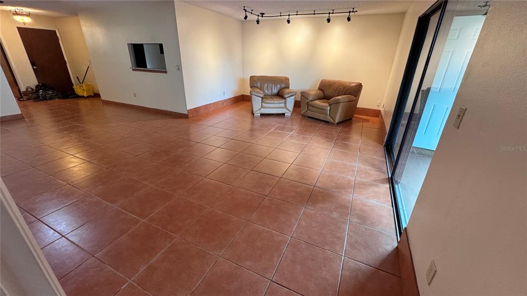 A living room with terracotta tile flooring, two leather armchairs, and track lighting — 2657 EXUMA WAY, WINTER PARK, FL