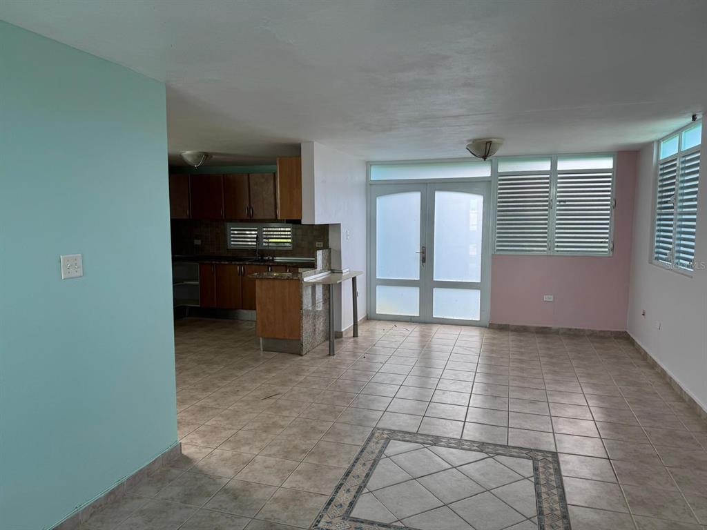 An open-concept living area with tile floors, a kitchen, and glass double doors — CALLE RIO PITAHAYA RIVER EDGE HILLS UNIT 120, LUQUILLO, PR