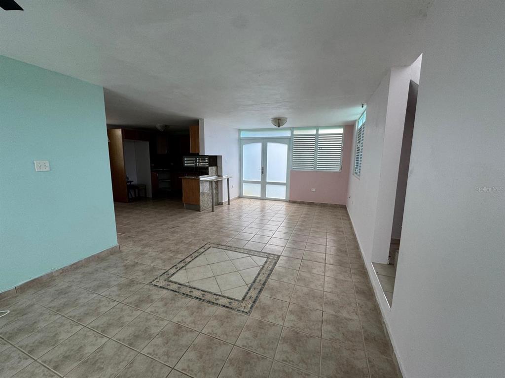 An open-concept living area features tiled floors, a kitchen island, and a glass door — CALLE RIO PITAHAYA RIVER EDGE HILLS UNIT 120, LUQUILLO, PR